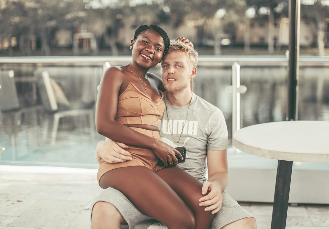 A smiling African woman and her European partner by the water